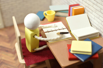 ノートに書き留めている木製人形の写真　勉強　執筆活動　宿題