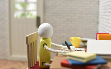 ノートに書き留めている木製人形の写真　勉強　執筆活動　宿題