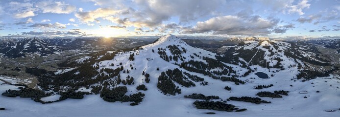 Sunset, alpine panorama, fantastic winter landscape with Hohe Salve, blue sky and snow, mountains and mountain valley, aerial view Skiwelt Wilder Kaiser ski area, Brixental, Tyrol, Austria
