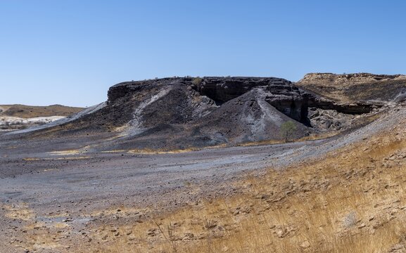 Dry landscape with yellow grass and black volcanic hills, Burnt Mountain, Damaraland, Kunene, Namibia