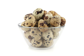 Fototapeta premium Quail eggs in a glass bowl isolated on white background. Natural patterned farm quail eggs.