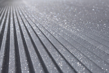 Fresh corduroy groomed snow on ski slope glistening