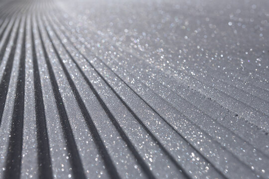 Fresh corduroy groomed snow on ski slope glistening