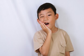 Studio portrait of a young boy touching his cheek while experiencing toothache or dental pain. Clean white background, perfect for healthcare, dentistry, and pain concept.