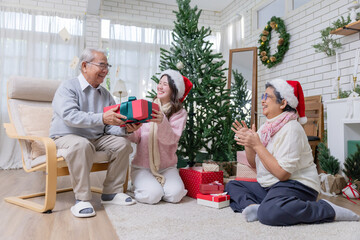 A young woman gives a red gift box to an her parrent for Christmas