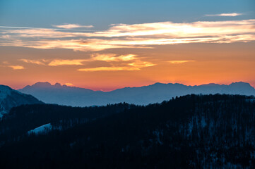 Obraz premium Colorful sunset painting mountain silhouettes and cloud layers