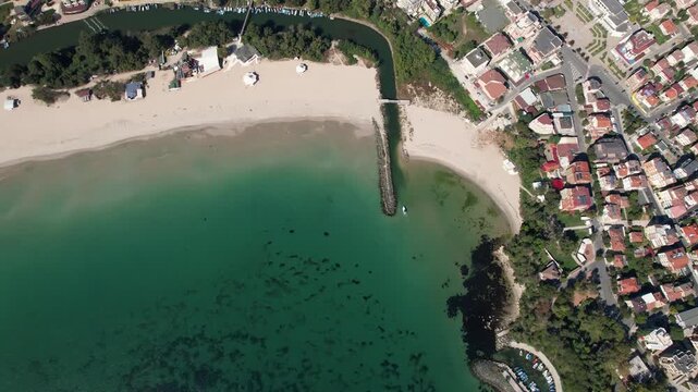 Aerial view of a sandy beach meeting the turquoise sea where a river flows into the ocean, creating a beautiful contrast of colors, Primorsko, Burgas, Bulgaria.