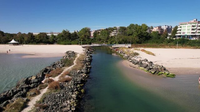 Aerial view of the channel flowing into the sea, with a bridge over it, contrasting white sand beaches and the green water, Primorsko, Burgas, Bulgaria.