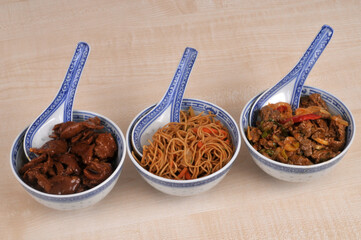 Repas style cuisine asiatique servi dans des bols  avec des cuill&egrave;res en gros plan isol&eacute; sur fond en bois