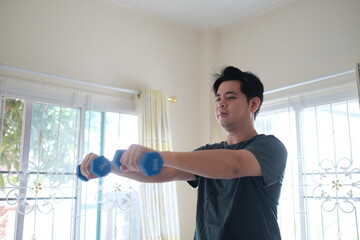 A man is lifting weights in a room with a window