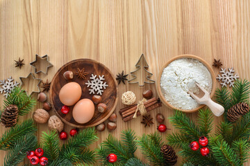 Holiday baking preparation with eggs, flour, and festive сhristmas decorations on wooden table