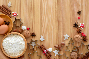 Holiday baking setup with flour, eggs, and festive cookie cutters on a wooden table