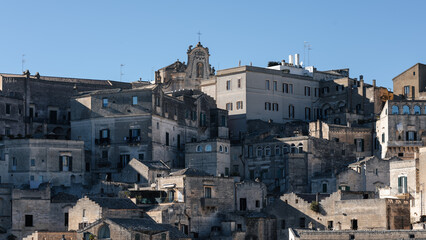 historic sassi di matera stone houses and ancient limestone buildings under a clear blue sky,...