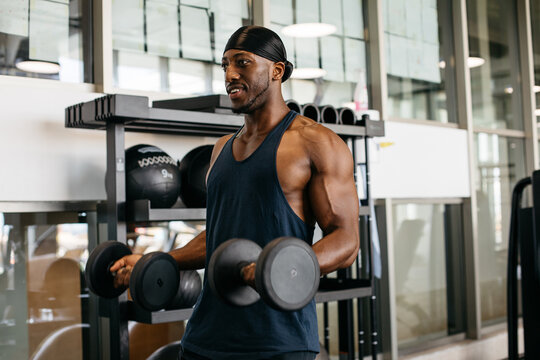 Muscular man performing dumbbell curl in gym. Athletic man lifting dumbbells during strength training workout in a modern gym.