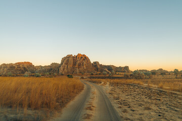 Isalo, Madagascar: Dirt road winding through savanna towards sunlit rock formations