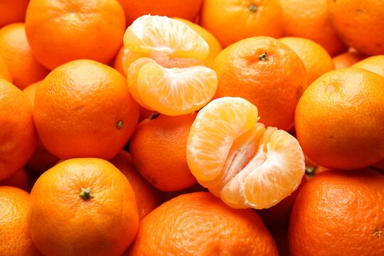 Many whole and peeled tangerines as background, closeup