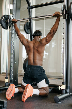 Powerful back workout on smith machine by muscular athlete. Strong athletic man performing wide grip lat pulldown emphasizing back muscles.