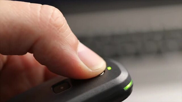 Close-up of Hand Activating Electronic Device with Button