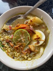 Traditional Indonesian Soto Soup with Lime, Boiled Egg, and Fried Shallots