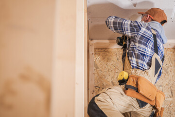 Carpenter Working on Drywall Installation in Indoor Construction Area