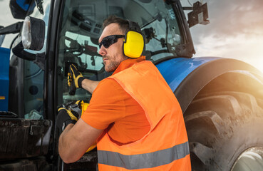 Worker Operates Tractor in Field During Late Afternoon Hours for Farm Tasks