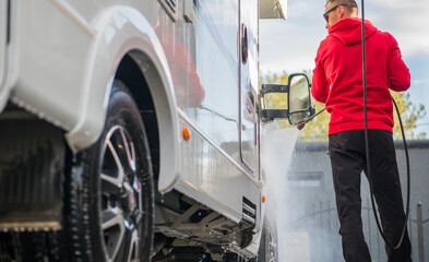 Man Washes a Motorhome RV at a Car Wash in the Afternoon Light