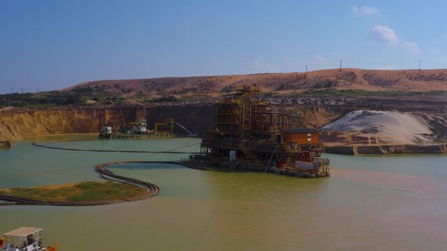 Aerial view of a mining operation featuring a large structure on the water surrounded by earthworks, creating a stark contrast, Moma, Nampula Province, Mozambique.