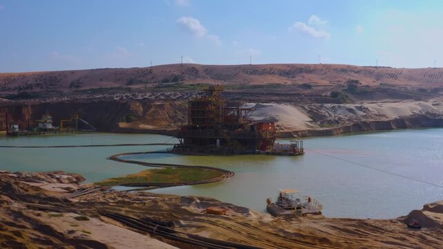 Aerial view of mining operation with machinery in water, contrasting the arid landscape with the light blue water body, Moma, Nampula Province, Mozambique.
