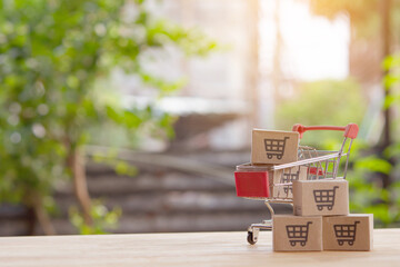Mini shopping cart with cardboard boxes on wooden table