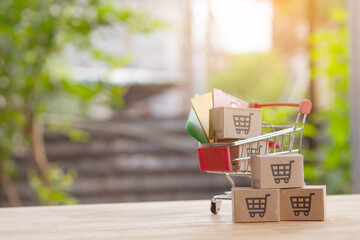 Mini shopping cart with cardboard boxes and credit card on wooden table