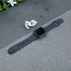 Smartwatch and wireless earbuds placed on concrete surface outdoors in minimal style