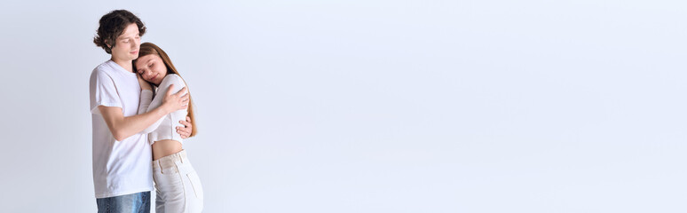 Young couple shares a joyful embrace in a stylish grey studio setting