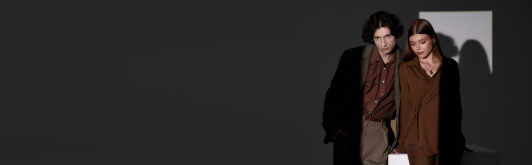 Stylish young couple showcases elegant fashion in a modern studio setting