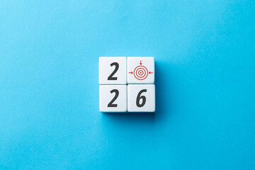 2026 business goals and target concept. White wooden cubes showing year 2026 with red bullseye icon on blue background. Creative vision, planning, and strategy for future success and achievement.