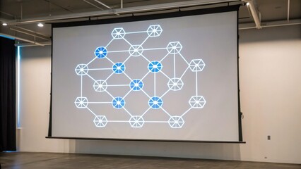 A digital presentation slide displays interconnected shapes in blue and white, illustrating a complex network or system on a large screen.