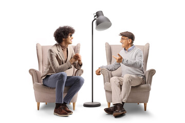 Young man and elderly man sitting in armchairs and having a conversation