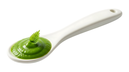 A white spoon holds a dollop of vibrant green puree or sauce