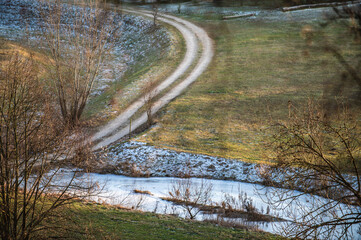 Aufsicht eisbedeckte Wasserfl&auml;che Flutmulde in Neckartenzlingen mit kurvigem Fahrweg an Wiese