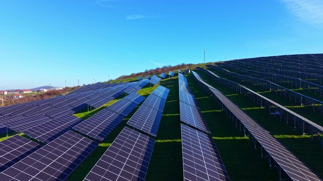 Rows of gleaming solar panels stretch across gently sloped hills, harnessing sunlight for energy in a beautiful natural setting. The scene evokes a sense of innovation and harmony.