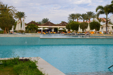 Obraz premium Resort Swimming Pool with Lounge Chairs and Palm Trees