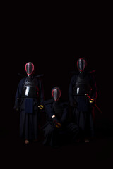 Naklejka premium Professional kendo athlete in uniform posing with shinai sword in black background with blue and red color lighting
