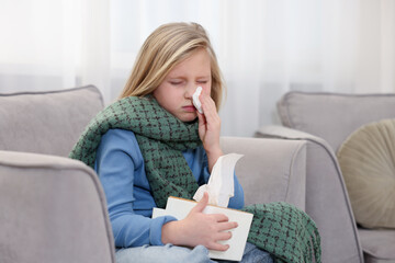 Little girl with runny nose at home. Cold symptom