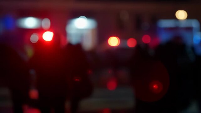 Blurred crowd of people with emergency vehicle lights in the background. Scene depicting urgency and response in a public safety situation