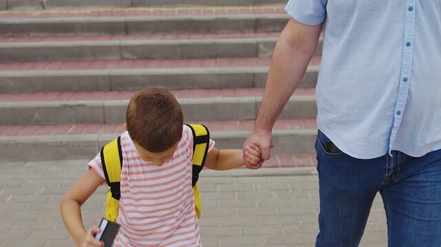 Holding hands for security, Children crossing city roads, Father and child street protection, Safe journey to school, Crossing at pedestrian lines, Worry-free school commute, Yellow backpack for