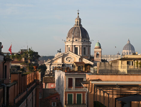 Elevated view across the rooftops of Rome, Italy, featuring the domes of historic churches illuminated by warm evening light. The timeless skyline showcases the Eternal City's remarkable blend of Rena