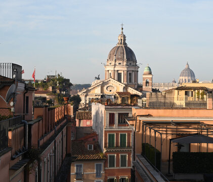 Elevated view across the rooftops of Rome, Italy, featuring the domes of historic churches illuminated by warm evening light. The timeless skyline showcases the Eternal City's remarkable blend of Rena