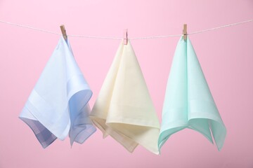 Stylish handkerchiefs hanging from string against pink background