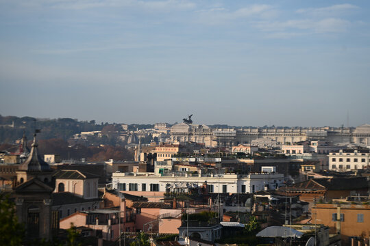 Elevated view across the rooftops of Rome, Italy, featuring the domes of historic churches illuminated by warm evening light. The timeless skyline showcases the Eternal City's remarkable blend of Rena