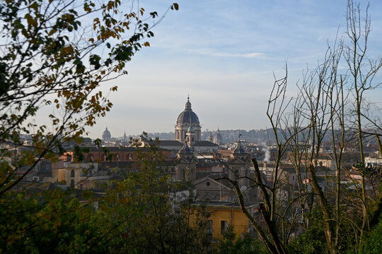 Elevated view across the rooftops of Rome, Italy, featuring the domes of historic churches illuminated by warm evening light. The timeless skyline showcases the Eternal City's remarkable blend of Rena