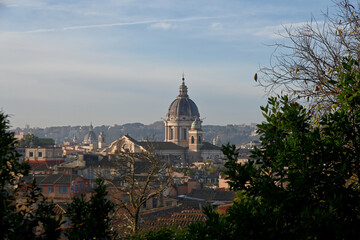 Obraz premium Elevated view across the rooftops of Rome, Italy, featuring the domes of historic churches illuminated by warm evening light. The timeless skyline showcases the Eternal City's remarkable blend of Rena